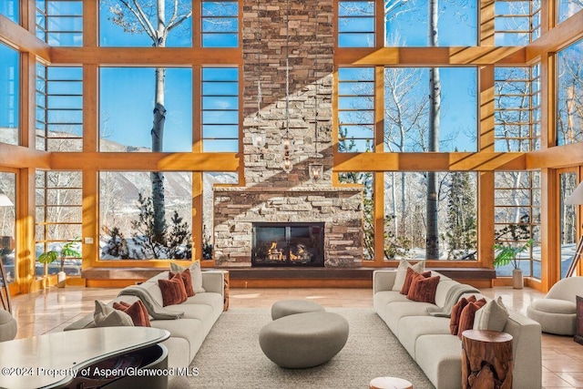 living room with a stone fireplace, tile patterned flooring, and a towering ceiling