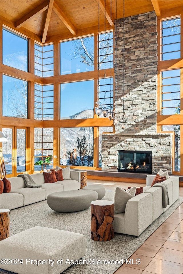 tiled living room featuring a high ceiling, a stone fireplace, floor to ceiling windows, and wooden ceiling