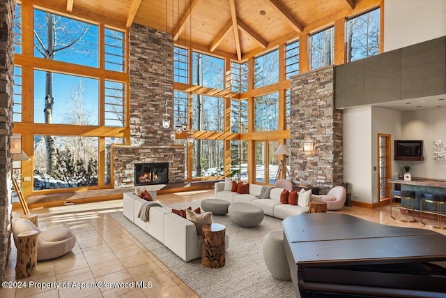 living room featuring beamed ceiling, high vaulted ceiling, a stone fireplace, and wood ceiling