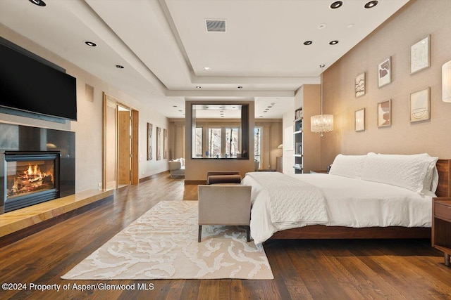 bedroom with hardwood / wood-style floors and a tray ceiling