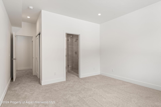 unfurnished bedroom with ensuite bathroom and light colored carpet