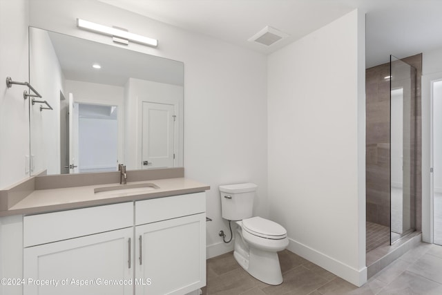 bathroom with toilet, vanity, and tiled shower