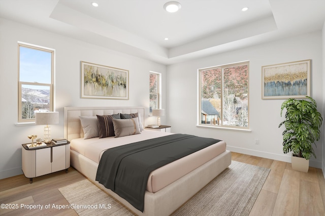 bedroom with a tray ceiling and light hardwood / wood-style floors