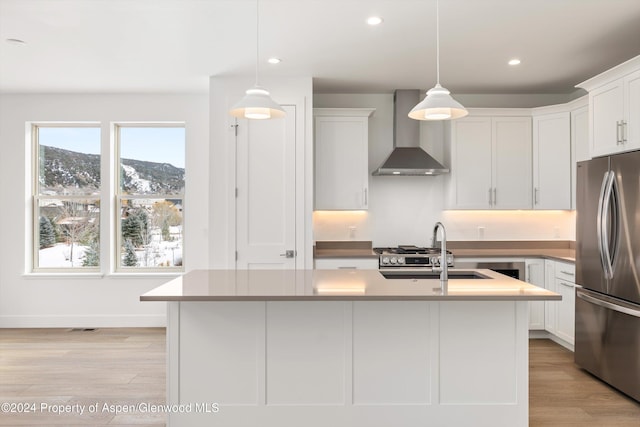 kitchen with wall chimney exhaust hood, a mountain view, hanging light fixtures, and stainless steel refrigerator