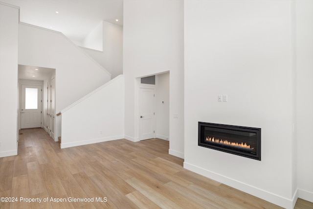 unfurnished living room featuring light hardwood / wood-style flooring and high vaulted ceiling