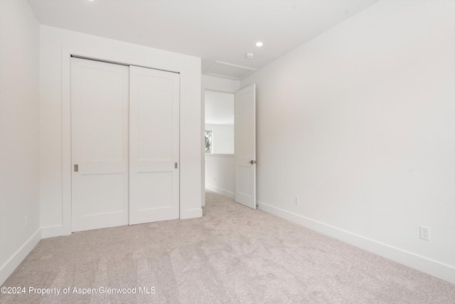 unfurnished bedroom with light carpet and a closet