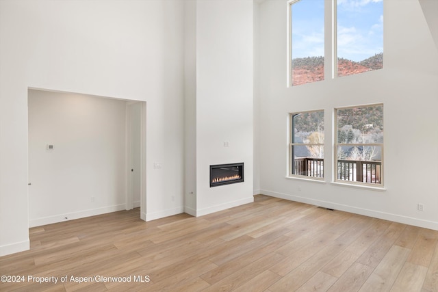 unfurnished living room featuring light hardwood / wood-style floors and a high ceiling