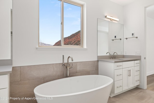 bathroom featuring tile patterned flooring, vanity, a tub, and tile walls