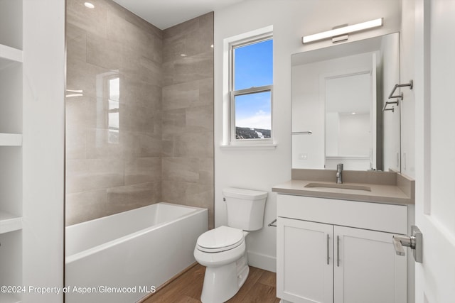 full bathroom with hardwood / wood-style floors, vanity, toilet, and tiled shower / bath