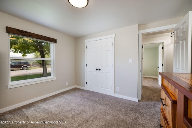 unfurnished bedroom featuring carpet, baseboards, and a closet