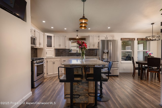 kitchen with stainless steel appliances, dark wood-type flooring, white cabinets, tasteful backsplash, and baseboards