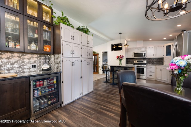 interior space featuring stainless steel appliances, beverage cooler, a chandelier, white cabinetry, and lofted ceiling