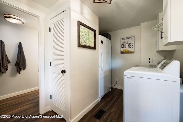 laundry area featuring separate washer and dryer, cabinet space, dark wood-type flooring, and baseboards