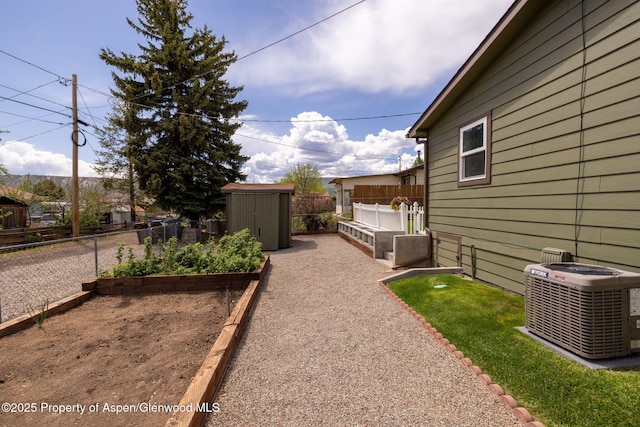 fenced backyard featuring central AC unit, a shed, an outbuilding, and a vegetable garden