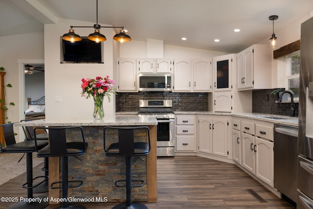 kitchen with stainless steel appliances, lofted ceiling, a sink, white cabinetry, and a breakfast bar area
