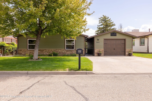 view of front of property featuring a front yard, concrete driveway, stone siding, and an attached garage