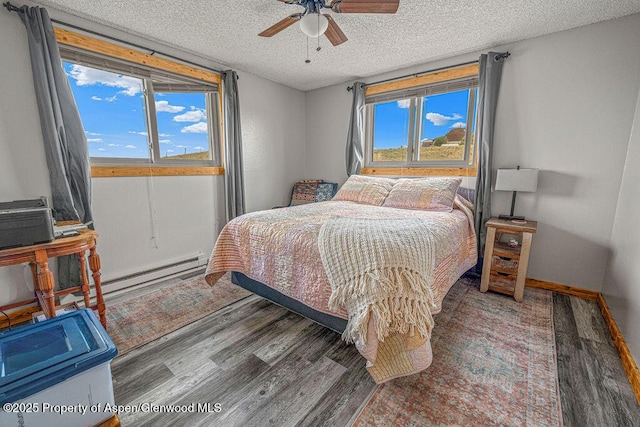 110 Western Ave, Craig, CO 81625 - bedroom featuring wood finished floors, a textured ceiling, multiple windows, a baseboard radiator, and ceiling fan