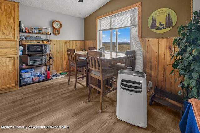 110 Western Ave, Craig, CO 81625 - dining area with a wainscoted wall, wooden walls, vaulted ceiling, a textured ceiling, and wood finished floors