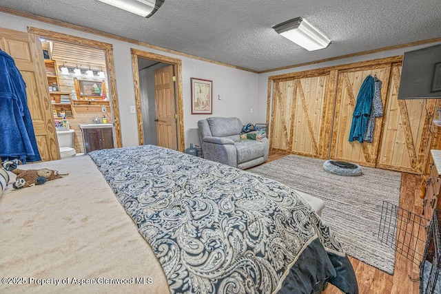 110 Western Ave, Craig, CO 81625 - bedroom featuring ornamental molding, a textured ceiling, wood finished floors, ensuite bath, and wood walls