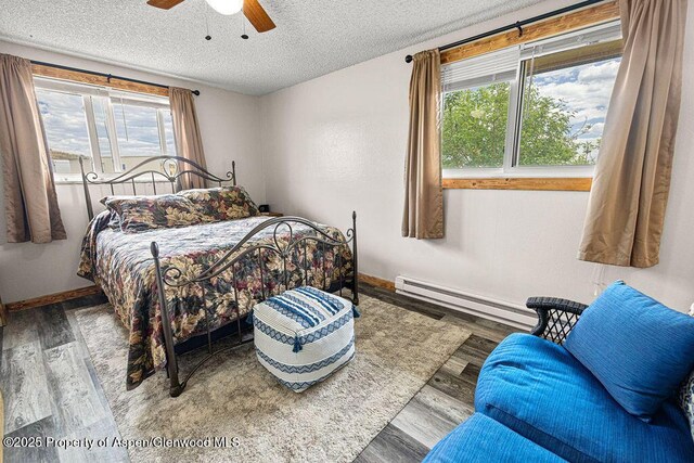 110 Western Ave, Craig, CO 81625 - bedroom with baseboard heating, a textured ceiling, wood finished floors, and a ceiling fan