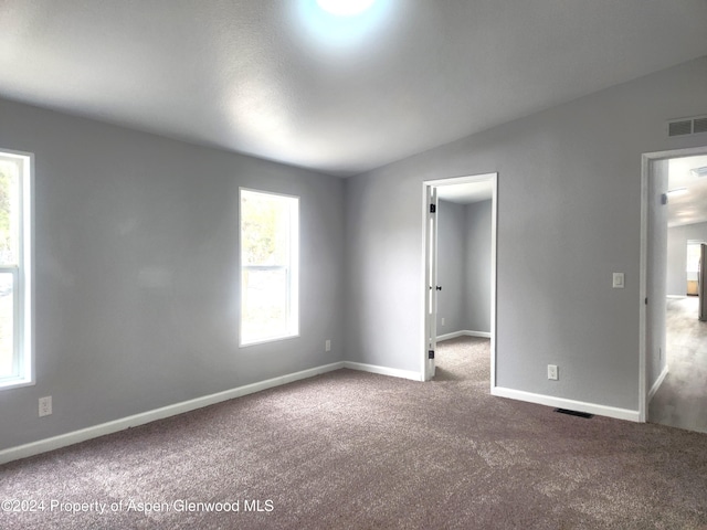 empty room featuring carpet and lofted ceiling