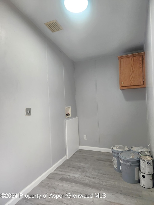 laundry area featuring cabinets, washer hookup, and light hardwood / wood-style floors