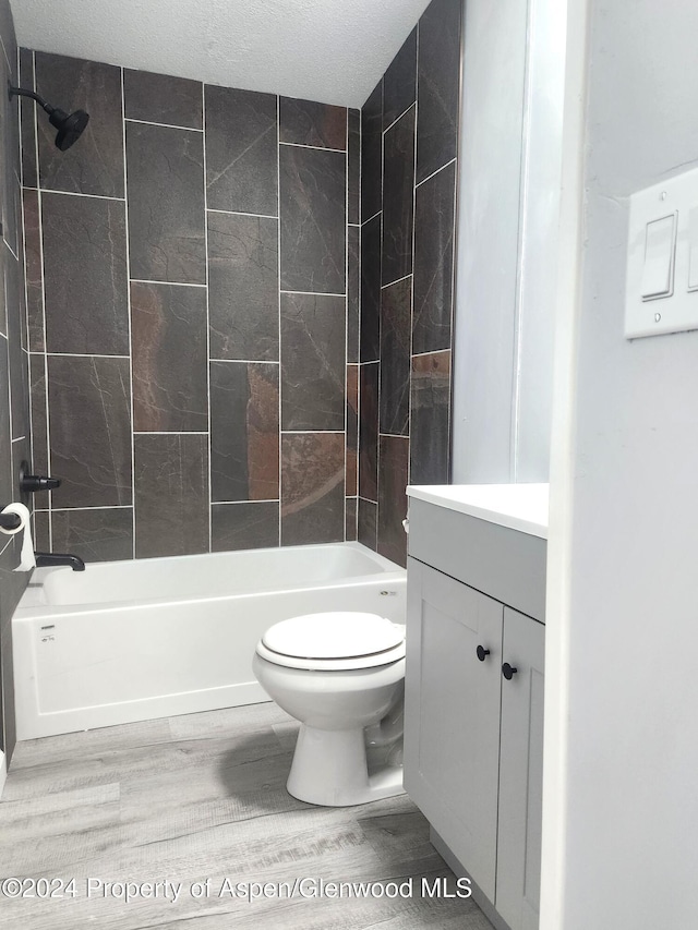 full bathroom featuring hardwood / wood-style flooring, vanity, toilet, and tiled shower / bath