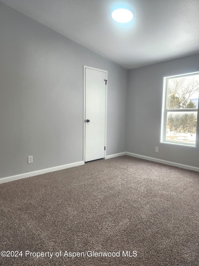 unfurnished room featuring carpet floors and vaulted ceiling