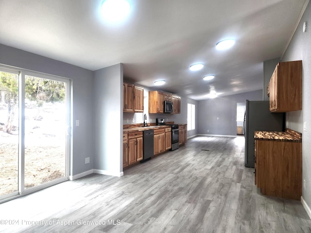 kitchen with dishwasher, stainless steel electric stove, sink, light wood-type flooring, and fridge