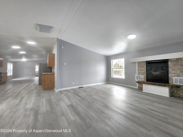 unfurnished living room with a fireplace, light hardwood / wood-style floors, and vaulted ceiling