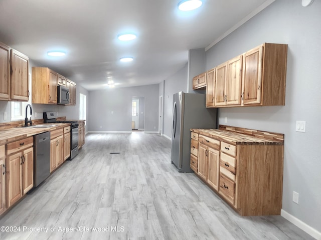 kitchen featuring crown molding, sink, light wood-type flooring, appliances with stainless steel finishes, and butcher block countertops