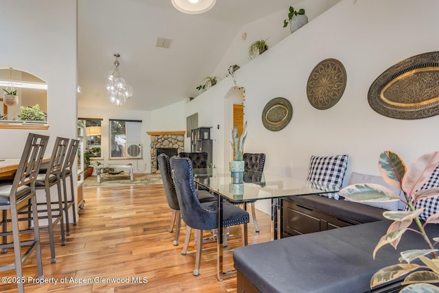 168 Current Dr, New Castle, CO 81647 - dining room with light wood-style flooring, high vaulted ceiling, a fireplace, and a chandelier