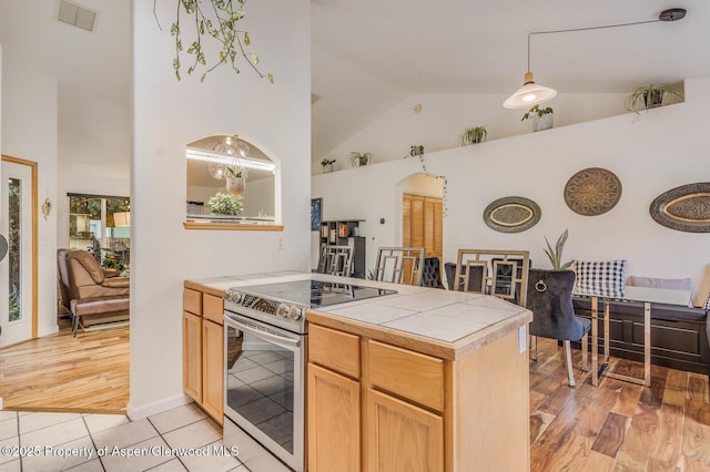 168 Current Dr, New Castle, CO 81647 - kitchen with stainless steel electric range, tile counters, high vaulted ceiling, a peninsula, and light wood-style floors