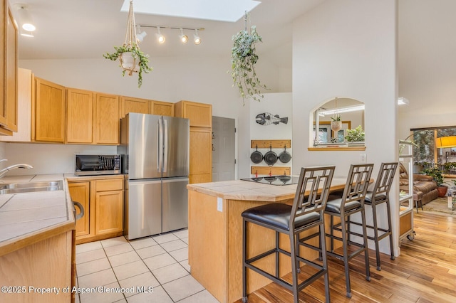 168 Current Dr, New Castle, CO 81647 - kitchen with stainless steel appliances, high vaulted ceiling, a breakfast bar area, tile countertops, and rail lighting