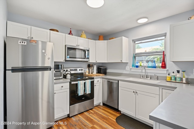 kitchen featuring white cabinets, sink, appliances with stainless steel finishes, and light hardwood / wood-style flooring