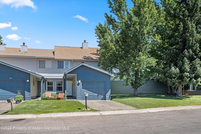 view of property with a garage and a front lawn