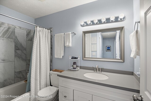 full bathroom with shower / tub combo with curtain, vanity, a textured ceiling, and toilet