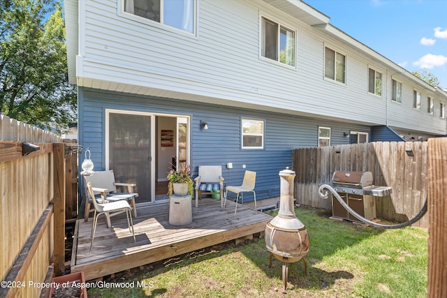 rear view of house with a yard, a deck, and a fire pit