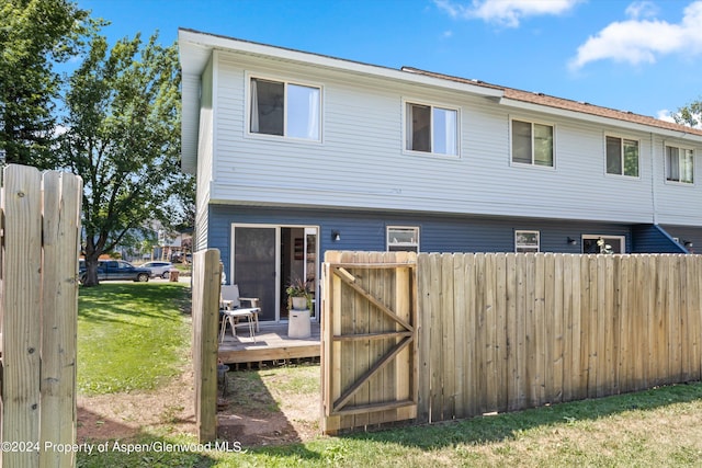 rear view of property featuring a wooden deck and a lawn