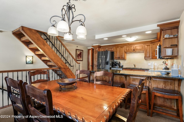 carpeted dining room with sink and an inviting chandelier