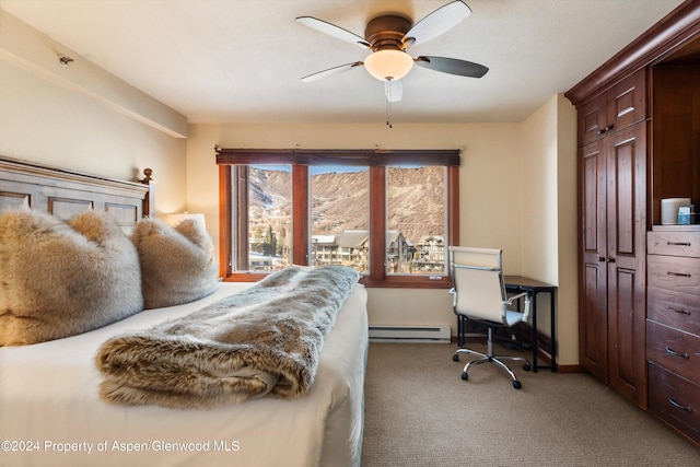 carpeted bedroom featuring ceiling fan, a mountain view, and a baseboard heating unit