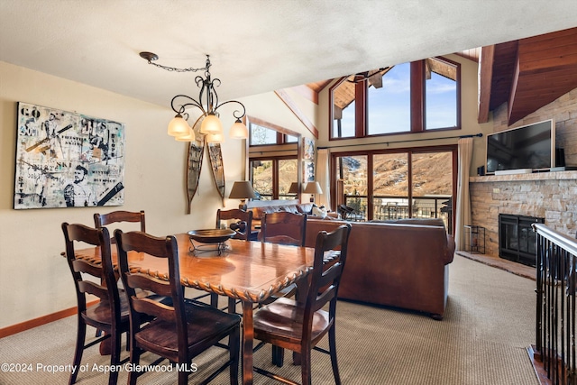 carpeted dining space featuring a fireplace, high vaulted ceiling, and a chandelier