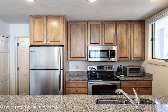 kitchen featuring light stone countertops, sink, and stainless steel appliances