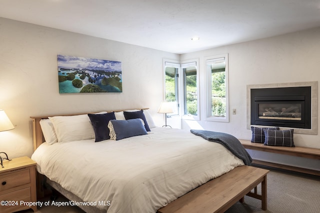 bedroom featuring carpet flooring and a tile fireplace