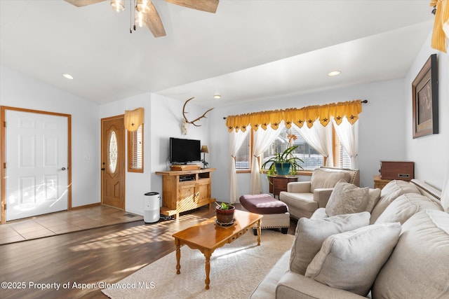 living room with hardwood / wood-style flooring, ceiling fan, and vaulted ceiling