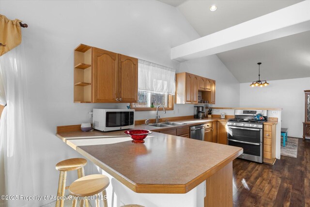 kitchen with pendant lighting, appliances with stainless steel finishes, sink, kitchen peninsula, and a breakfast bar