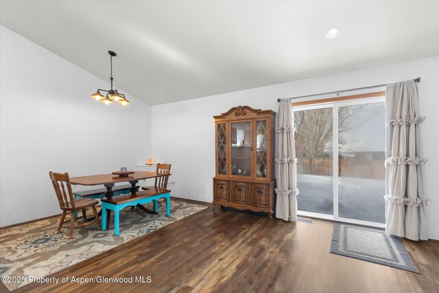 dining area with vaulted ceiling, dark wood-type flooring, and a chandelier