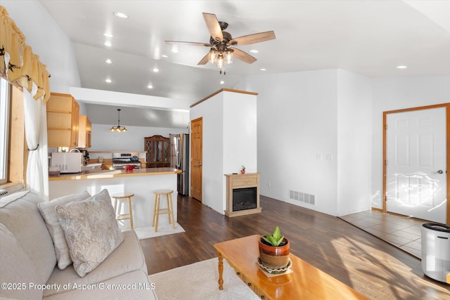 living room featuring ceiling fan, vaulted ceiling, and dark hardwood / wood-style flooring