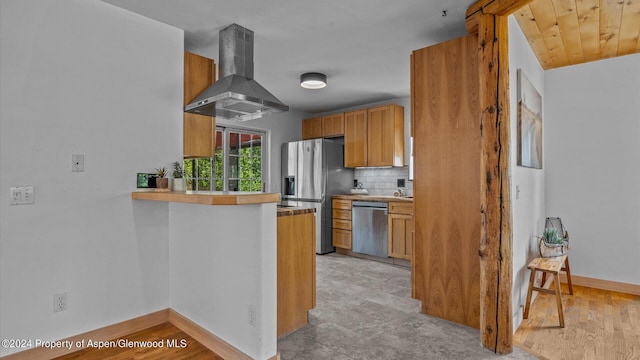 kitchen featuring a kitchen breakfast bar, wall chimney range hood, decorative backsplash, kitchen peninsula, and stainless steel appliances