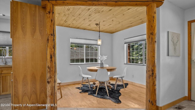 dining space with beam ceiling, a wealth of natural light, light hardwood / wood-style flooring, and wood ceiling